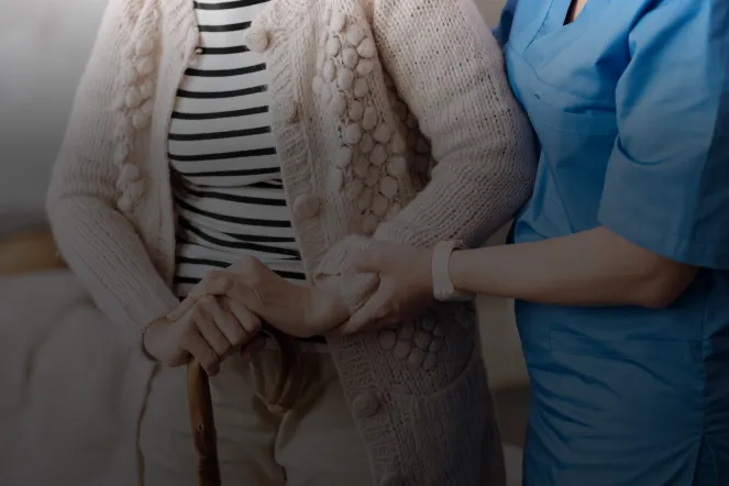 Pflegekraft stützt ältere Dame