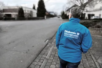 Andrea Schnackerts in blauer Diakoniejacke von hinten gesehen